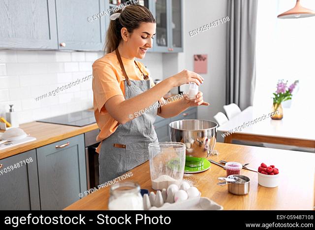 happy young woman cooking food on kitchen at home