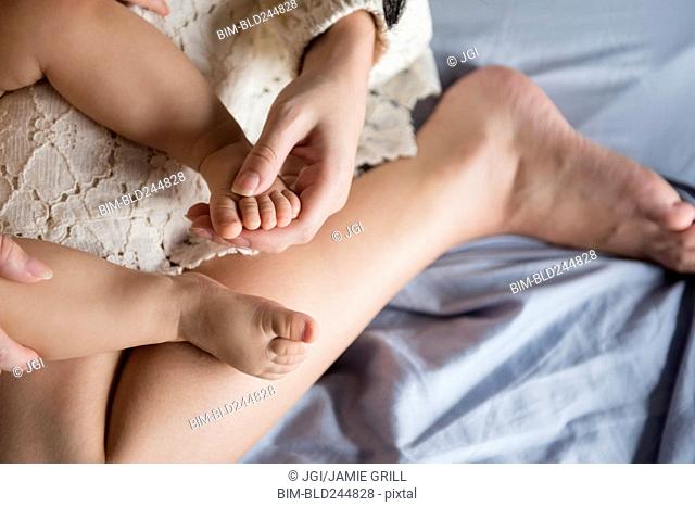 Caucasian mother holding foot of baby son