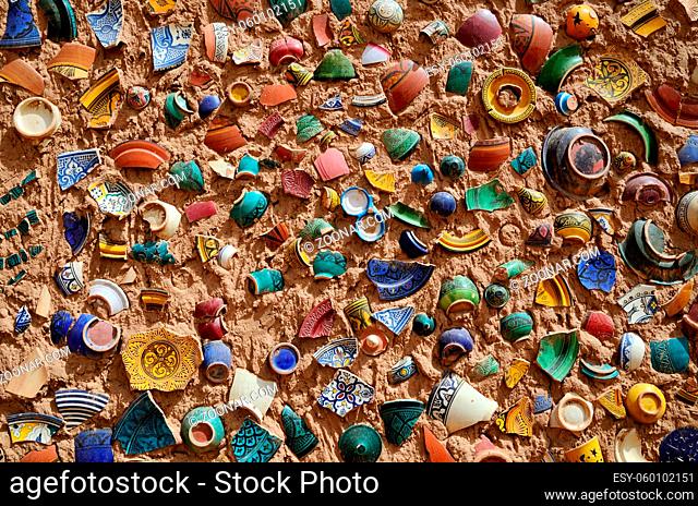 Clay wall background with fragments of broken traditional moroccan plates in a pottery shop in Morocco