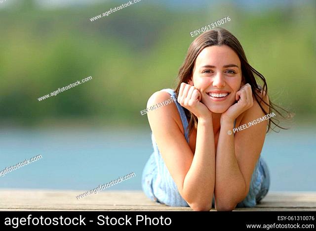 Happy woman looking at camera lying on pier