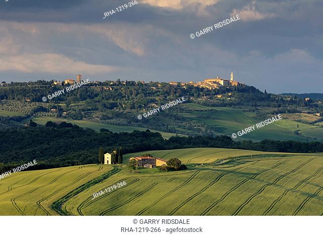 Looking across the Val d'Orcia and Chapel of Madonna di Vitaleta with the late evening sun illuminating the town of Pienza, UNESCO World Heritage Site, Tuscany