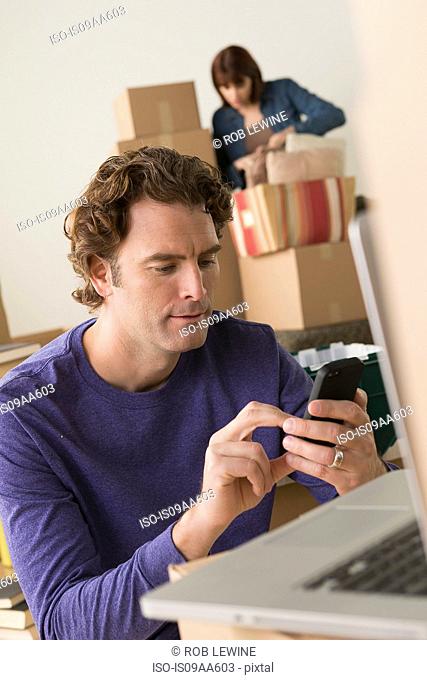 Man texting on cellphone whilst moving house
