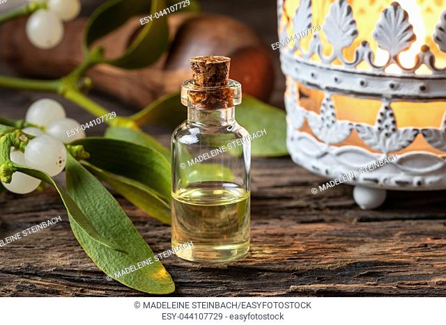 A bottle of essential oil with fresh mistletoe twigs