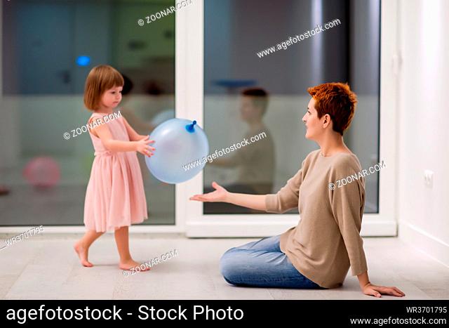 happy family spending time together young redhead mother and cute little daughter having fun while playing with balloons near the window on beautiful evening at...