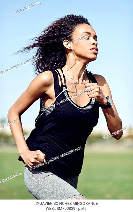 Sporty young woman with earphones running