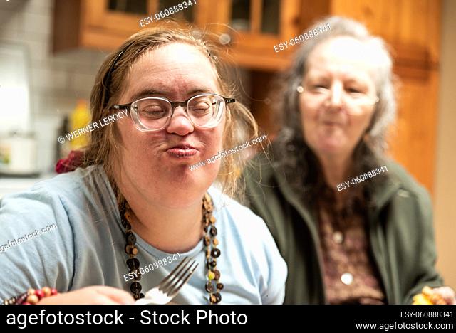 Hakendover, Flemish Brabant, Belgium - 09 20 2021: Disabled 39 year old woman and her 83 year old mother having fun in the kitchen at home