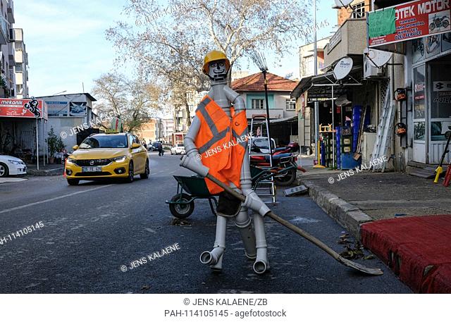 11.12.2018, Turkey, Tire: with a man made of pipes with hardhat and safety vest and a shovel, a trader frees the parking lot in front of his business in the...