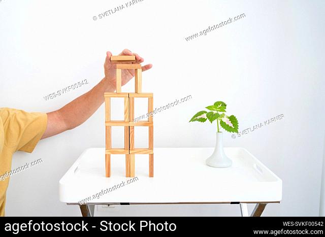Hand of man building wooden block tower on table