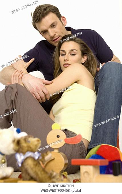 Young couple sitting on floor with toys, close-up