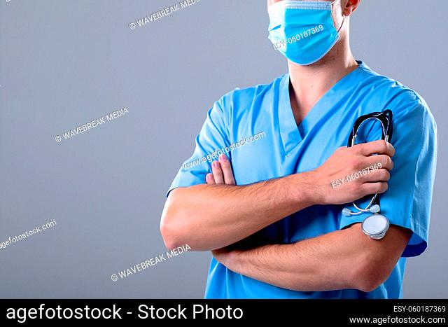 Caucasian male doctor wearing face mask holding stethoscope