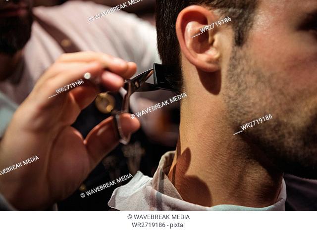Close-up of man getting his hair trimmed with scissor