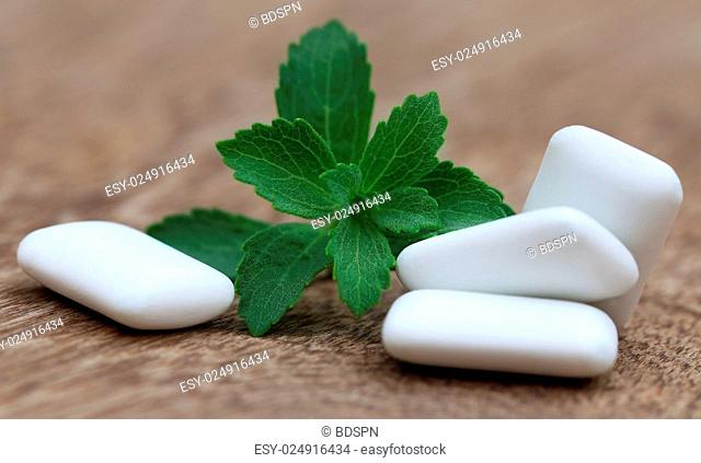Chewing gum with green stevia on wooden surface