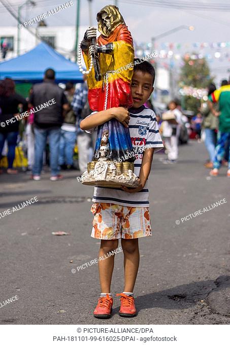 31 October 2018, Mexico, Mexico-City: A child carries a statue of the patron saint Santa Muerte to a shrine in the district of Tepito
