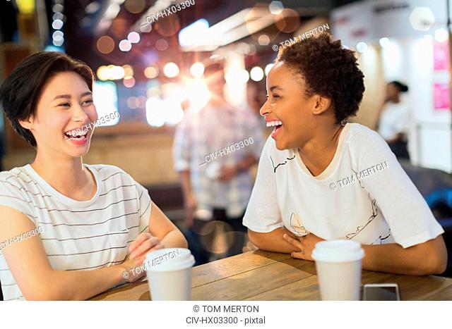 Laughing young women drinking coffee at cafe