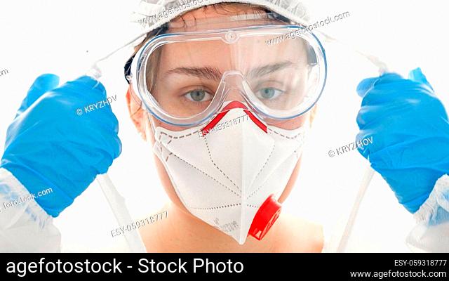 Exhausted and tired doctor looking in camera after taking off protective suit, goggles and facial medical mask. Medical workers fighting against covid-19 and...