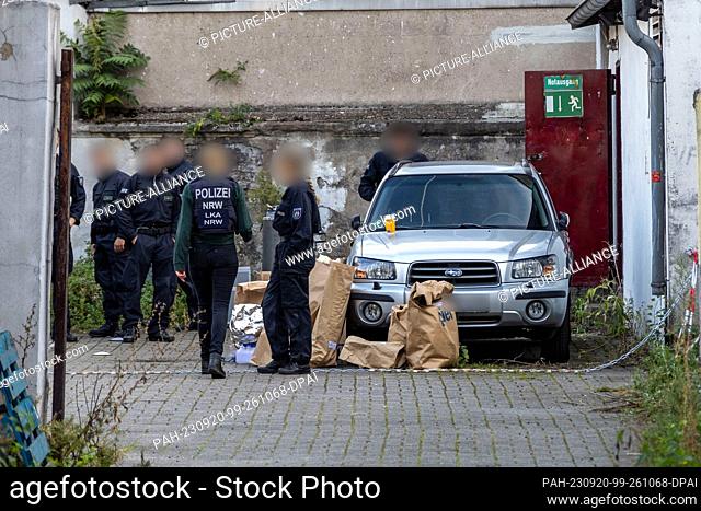 20 September 2023, North Rhine-Westphalia, Duisburg: Police officers stand in a backyard in downtown Duisburg, with paper bags of evidence on the ground