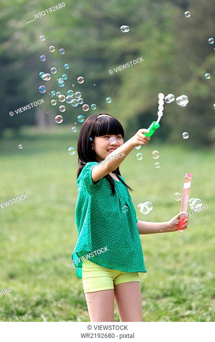 Girl making soap bubbles outdoors