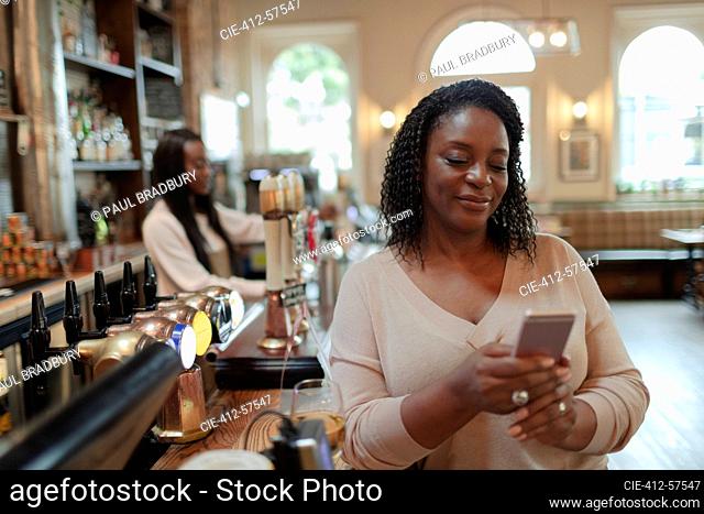 Woman using smart phone at bar