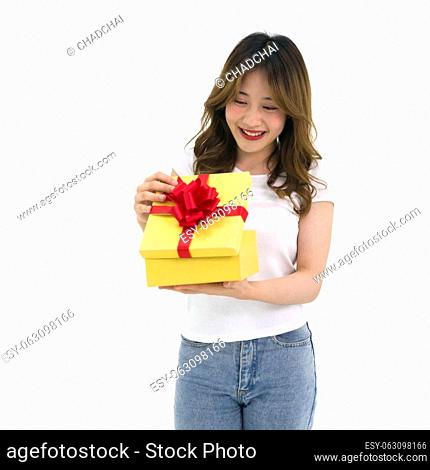 Young asian woman in white t-shirt and jean opening a gift box received for a special occasion. Portrait on white background with studio light