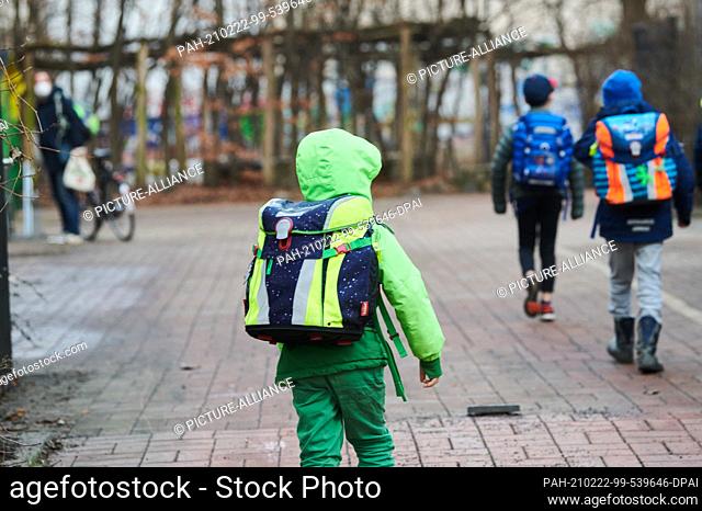 22 February 2021, Berlin: Three students walk to the entrance of an elementary school in Prenzlauer Berg with school bags