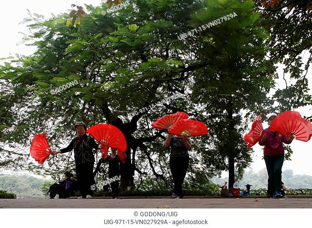 Early morning tai chi session along the banks of Hoan Kiem lake. Exercises with fans
