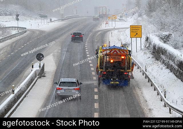 27 November 2023, Rhineland-Palatinate, Meilbrück: Cars and a gritting vehicle on the road in the driving snow on the B51