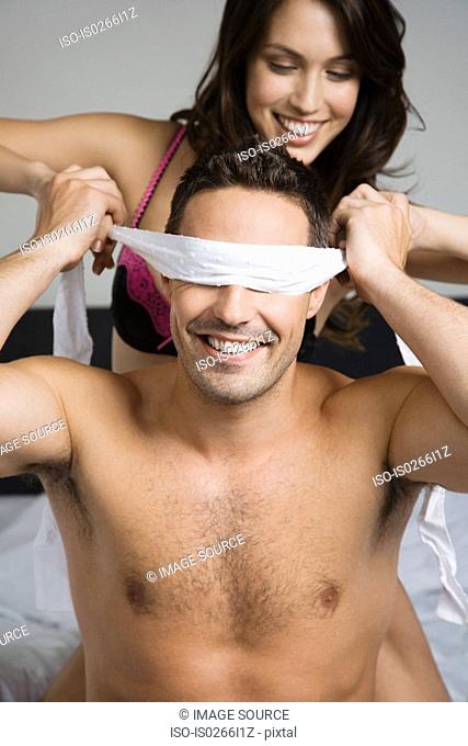 A woman blindfolding a man