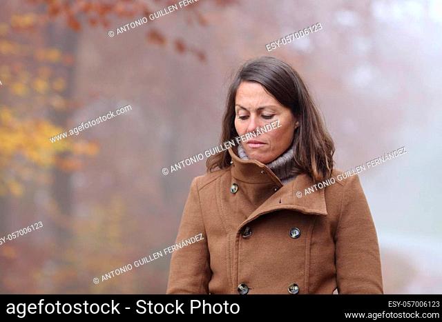 Sad woman walking alone complaining in a park in winter