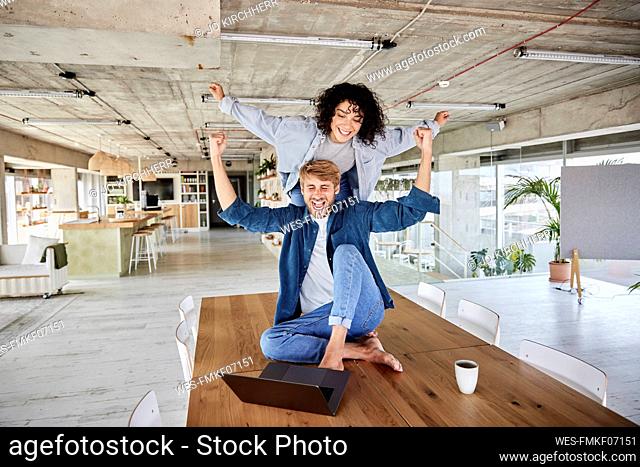 Couple with arms outstretched enjoying on table at loft