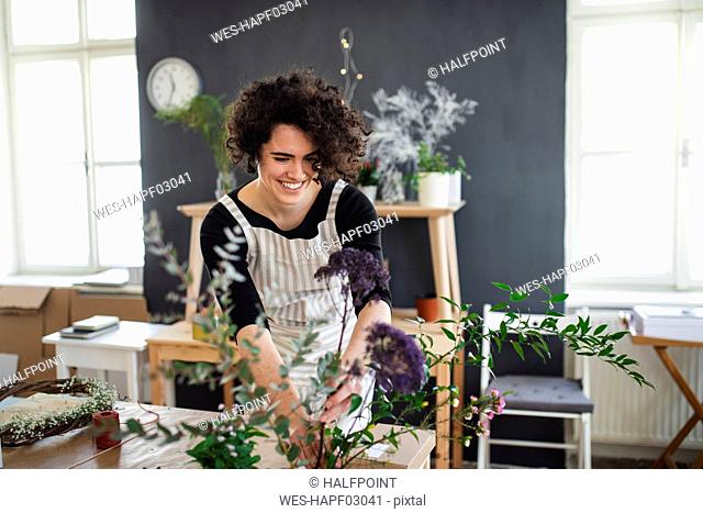 Smiling young woman arranging flowers in a small shop