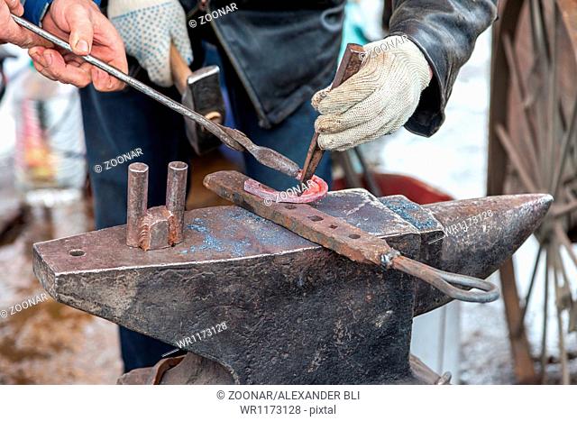 Blacksmith forges a hot horseshoe on the anvil