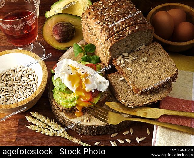homemade avocado and egg wholemeal bread sandwich with ingredients and wine cup in wood table background