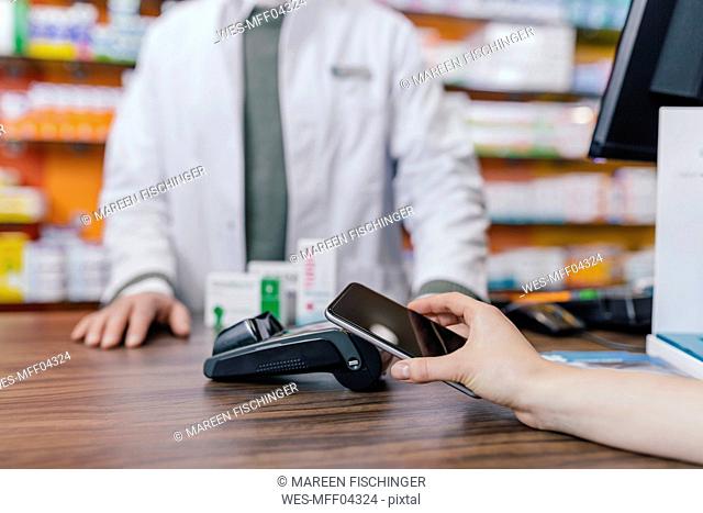 Close-up of customer paying cashless with smartphone in a pharmacy