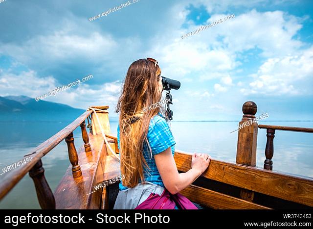 Woman on a boat with binocular watching birds in nature