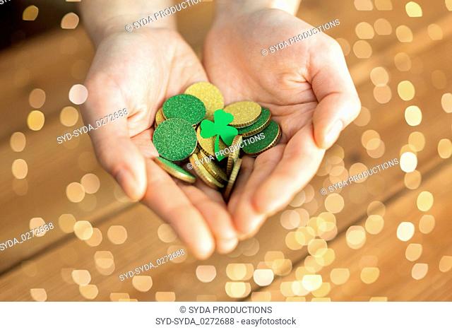 hands with golden coins and shamrock leaf