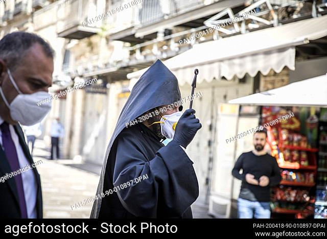 18 April 2020, Israel, Jerusalem: An Armenian priest wearing a face mask walks to the Church of the Holy Sepulchre as Orthodox Christians celebrate the ""Holy...