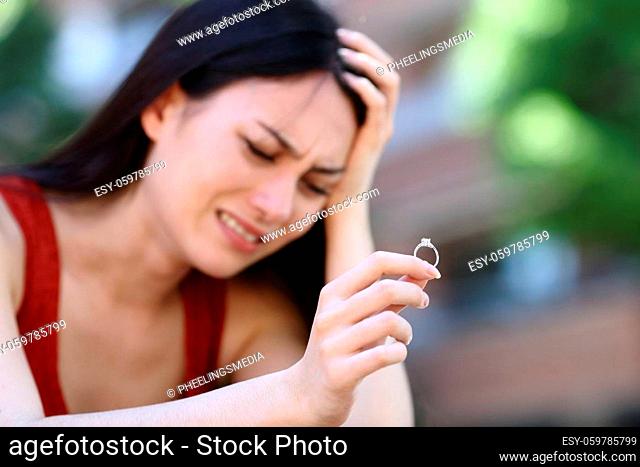 Sad asian woman complaining holding engagement ring in the street