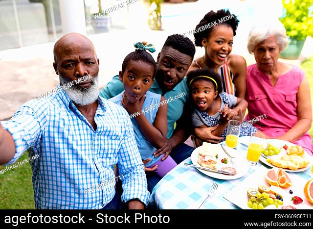 Portrait of three generational african american family taking selfie sitting at dining table