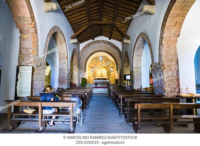 A pilgrim rests on a church bench. The Royal St. Mary's Church, also known as the Church of St. Benedict, was built in O Cebreiro in 1965â