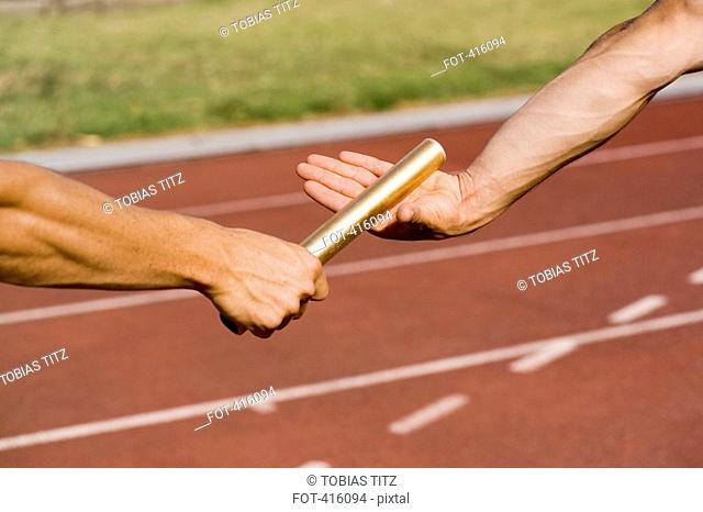 Two athletes exchanging a baton during a relay race