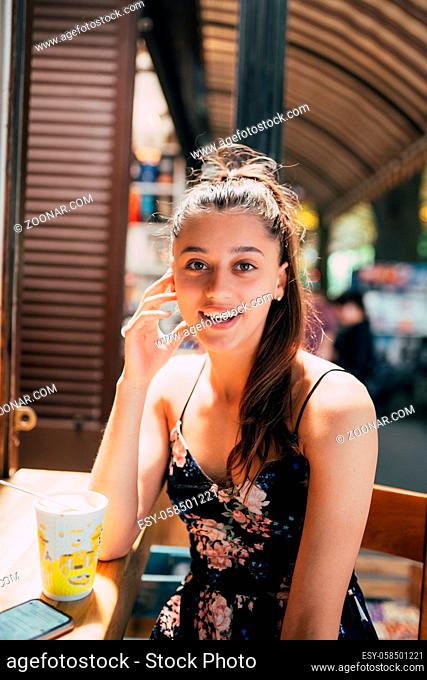 Attractive young caucasian woman sitting in street cafe, summer day