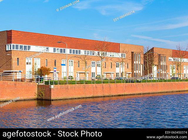 Row of modern brick houses along water in a family friendly suburban neighborhood in Veenendaal in the Netherlands