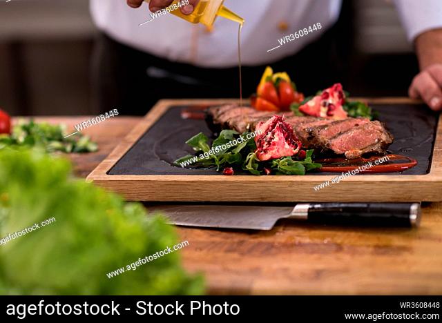 Chef finishing steak meat plate with Finally dish dressing and almost ready to serve at the table