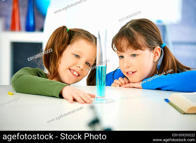 Elementary age school girls looking at test tube in chemistry class at primary school