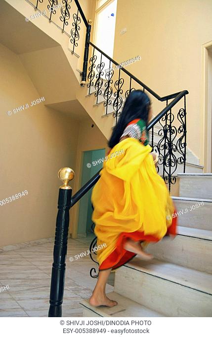 Young girl with yellow chunni stepping up briskly in house ; India MR704;PRMR704