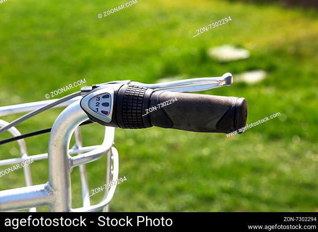 Close up detailed front view of black handle bar and bicycle gear on green background