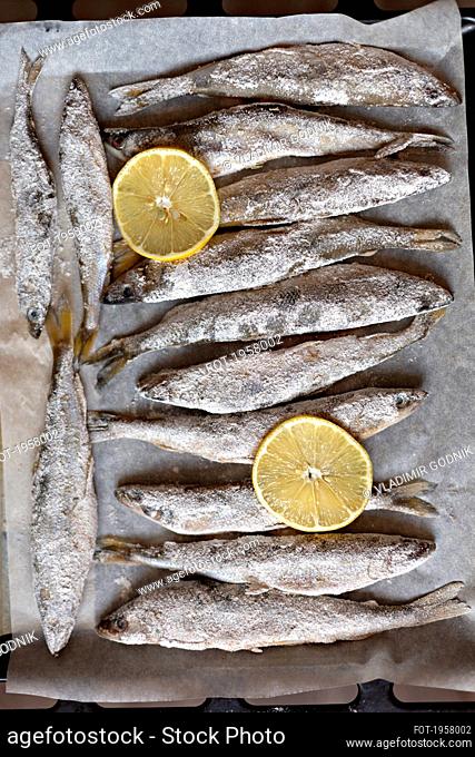 Salted whole fish and lemon slices on parchment paper