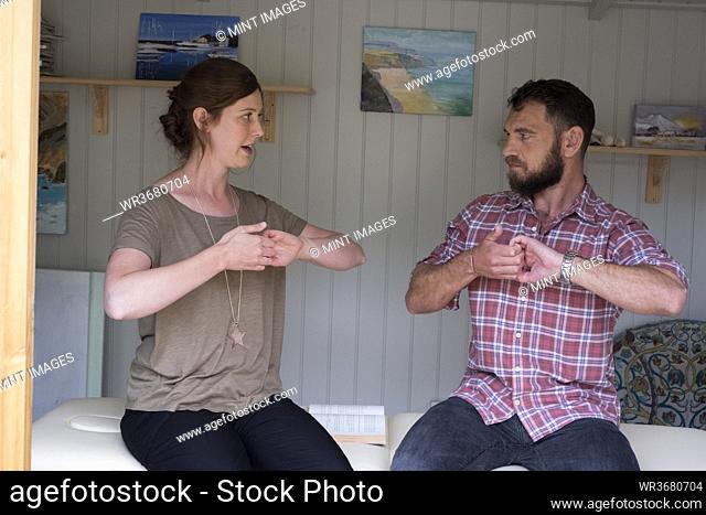 Man and female therapist with their hands clasped gripping the curled fingers