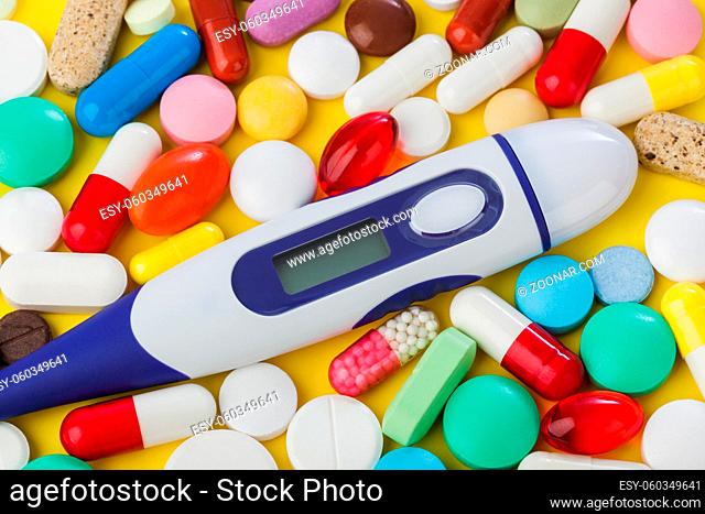 Pills and electronic thermometer with blank screen - abstract medical background