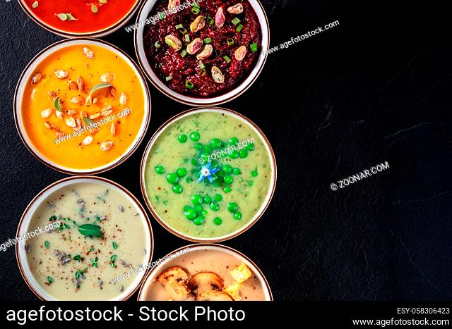 Vegan cream soup, top shot with copy space. A variety of pureed soups on a black background
